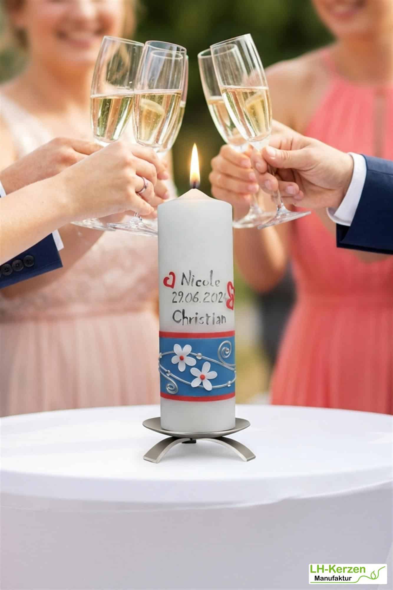 Hochzeitskerze mit weißen Blumen, blauem Band und Ringen