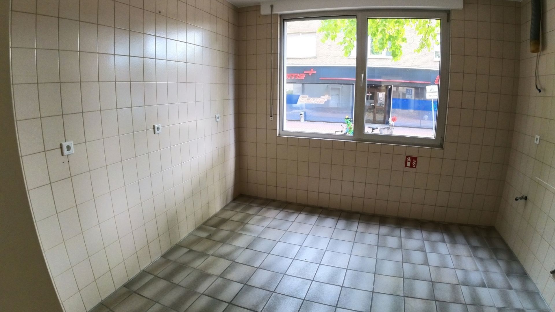 Ehemaliges Apothekenlabor vor dem Umbau Leerer, weiß gefliester Raum mit Fenster vor dem Ausbau zur Kerzengießerei