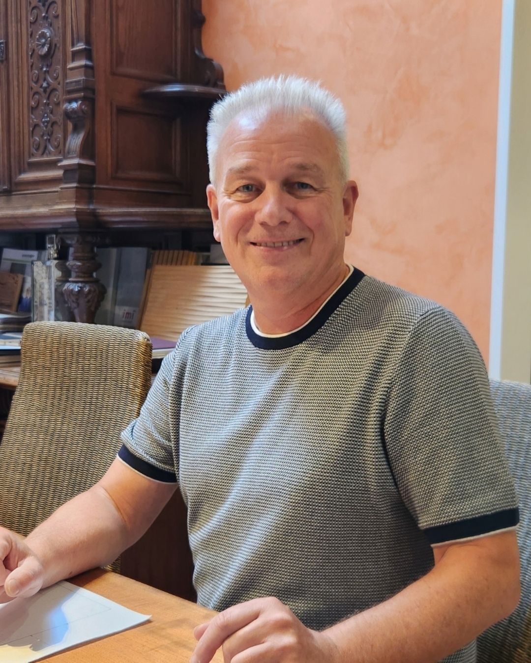 Tischlermeister sitzt an einem Tisch und blickt in die Kamera